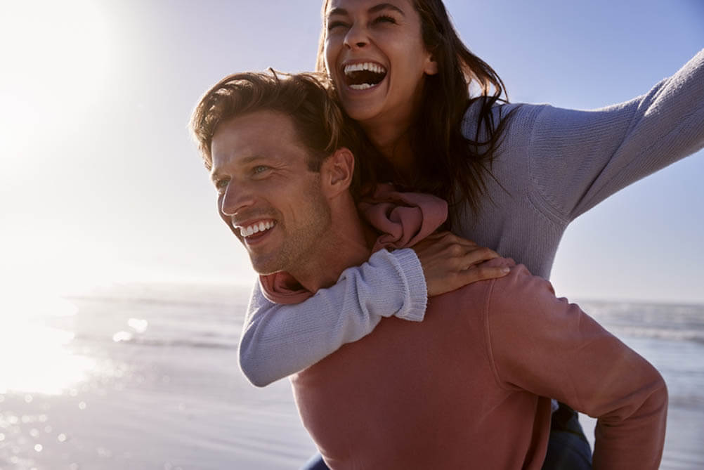 Man giving woman piggyback ride on beach