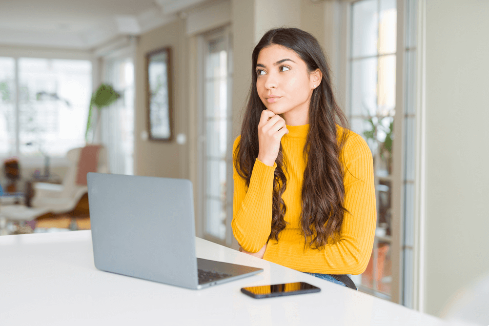 Woman using laptop with hand on chin thinking about how to predict lottery numbers 