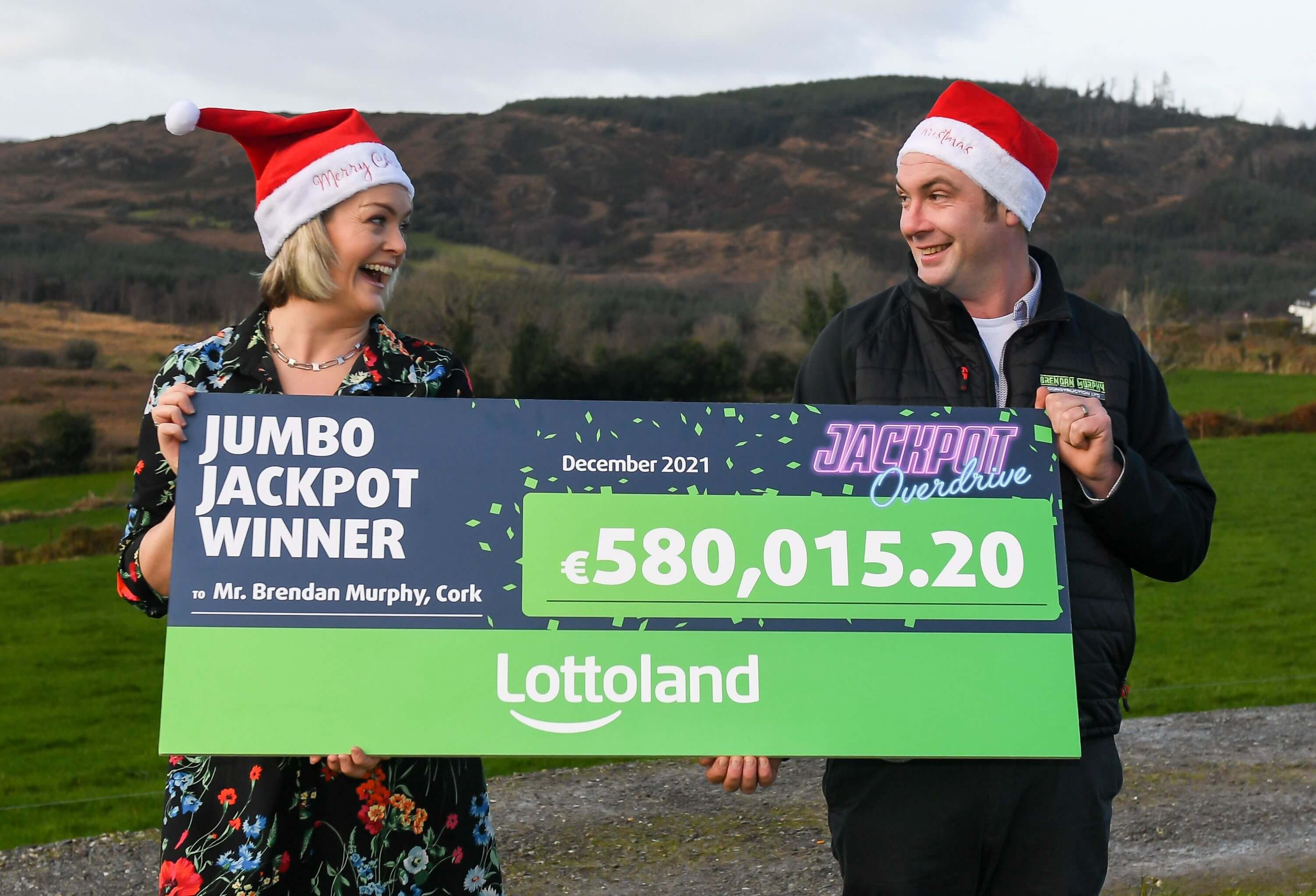 Lottoland Ireland Winner Brendan Murphy Lottoland winner holding up his cheque and smiling with his wife after winning the jackpot wearing Christmas hats to celebrate