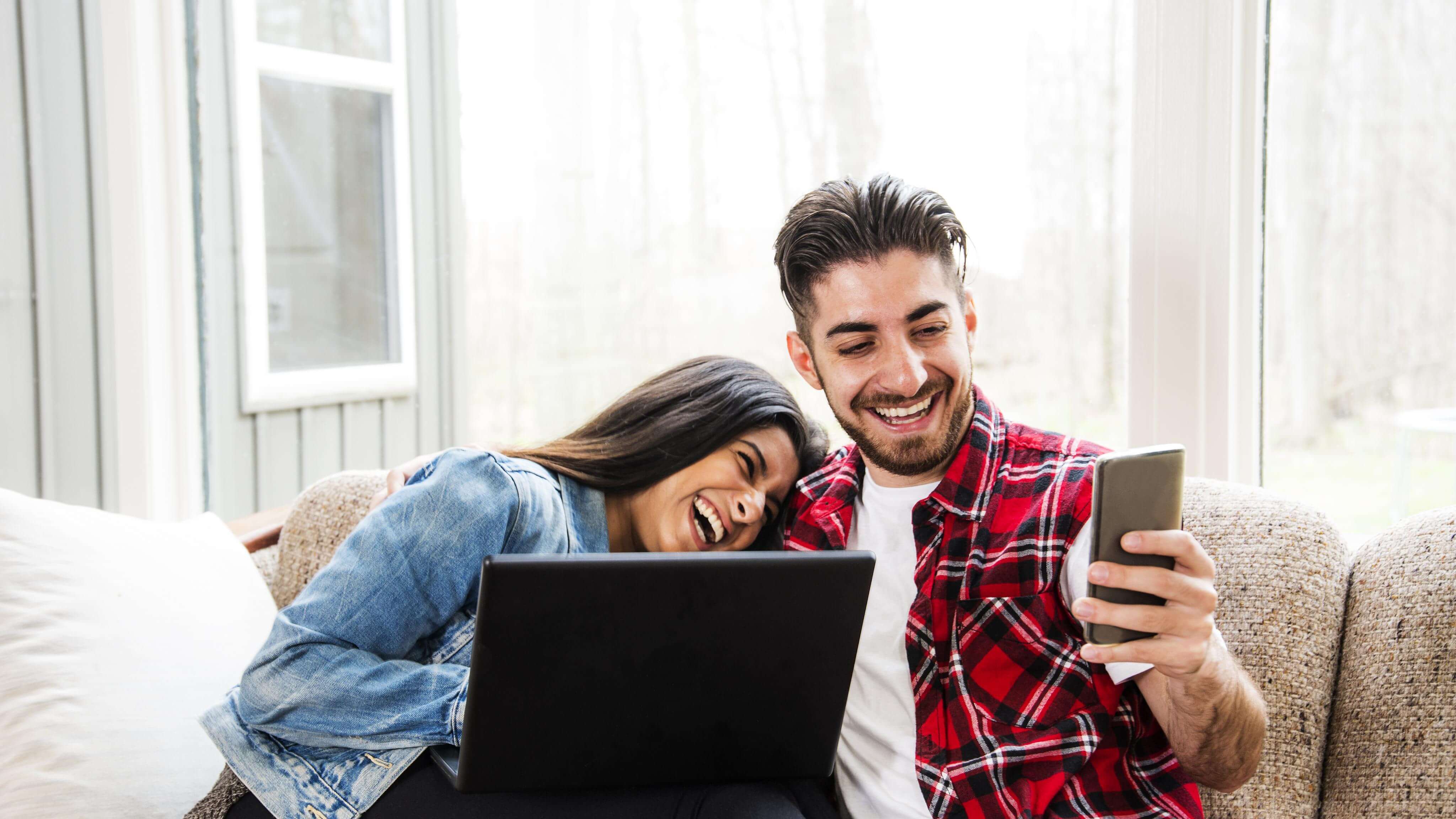 Happy Indian couple on their mobile devices playing the lottery online
