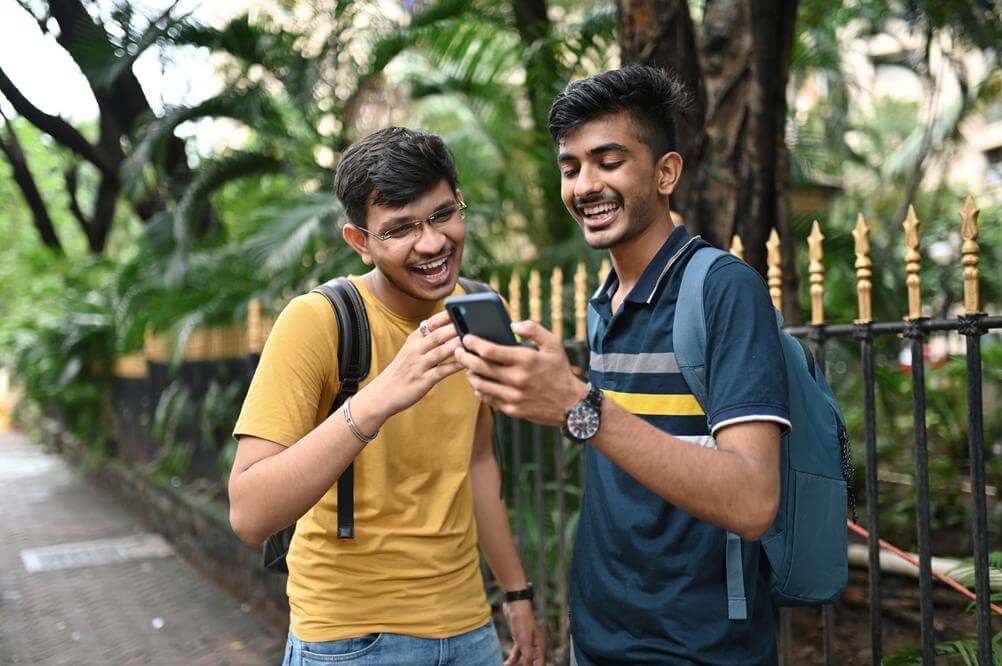 What are Mini Bets? Smiling Indian friends checking their Lottoland online lottery mini bets