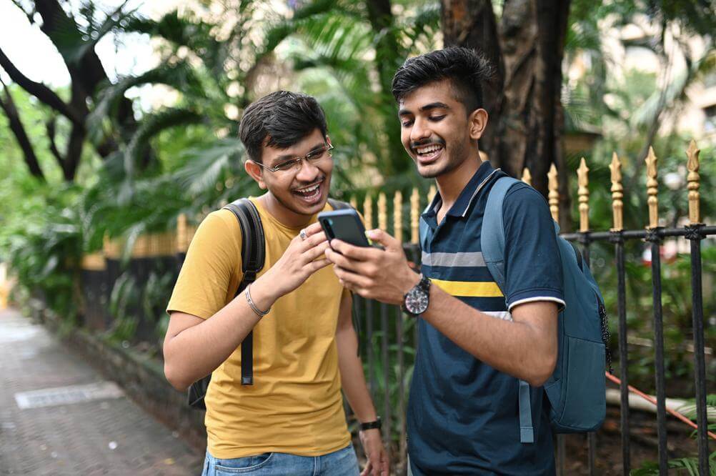 Smiling Indian friends checking their Lottoland online lottery mini bets