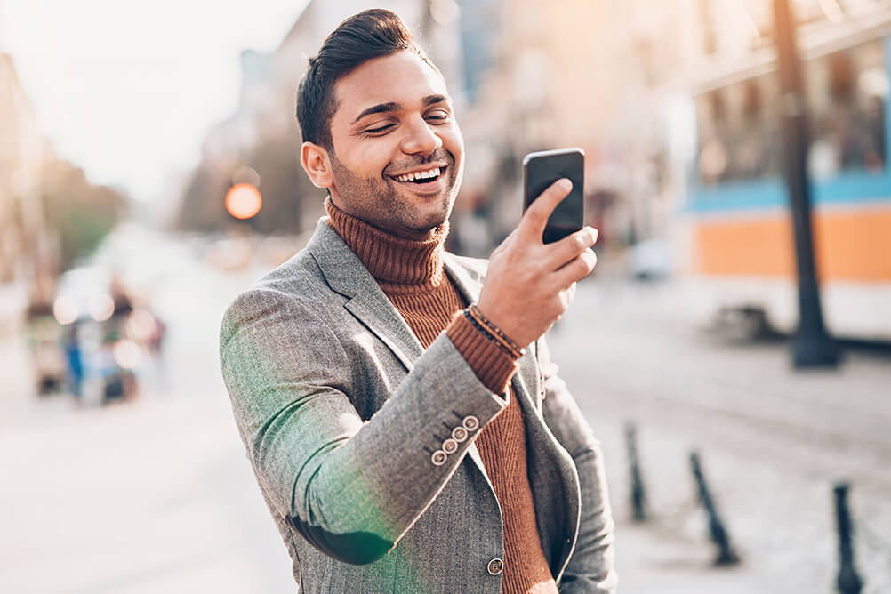 Smiling Indian man in suit checking lucky lottery numbers on mobile