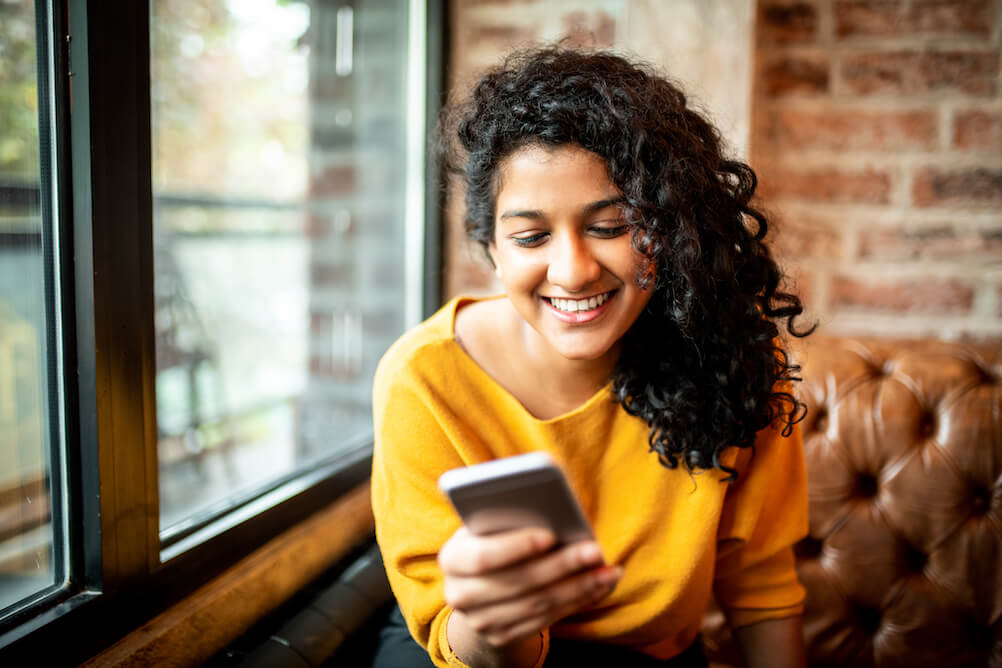 Happy woman using mobile to check lottery draw times